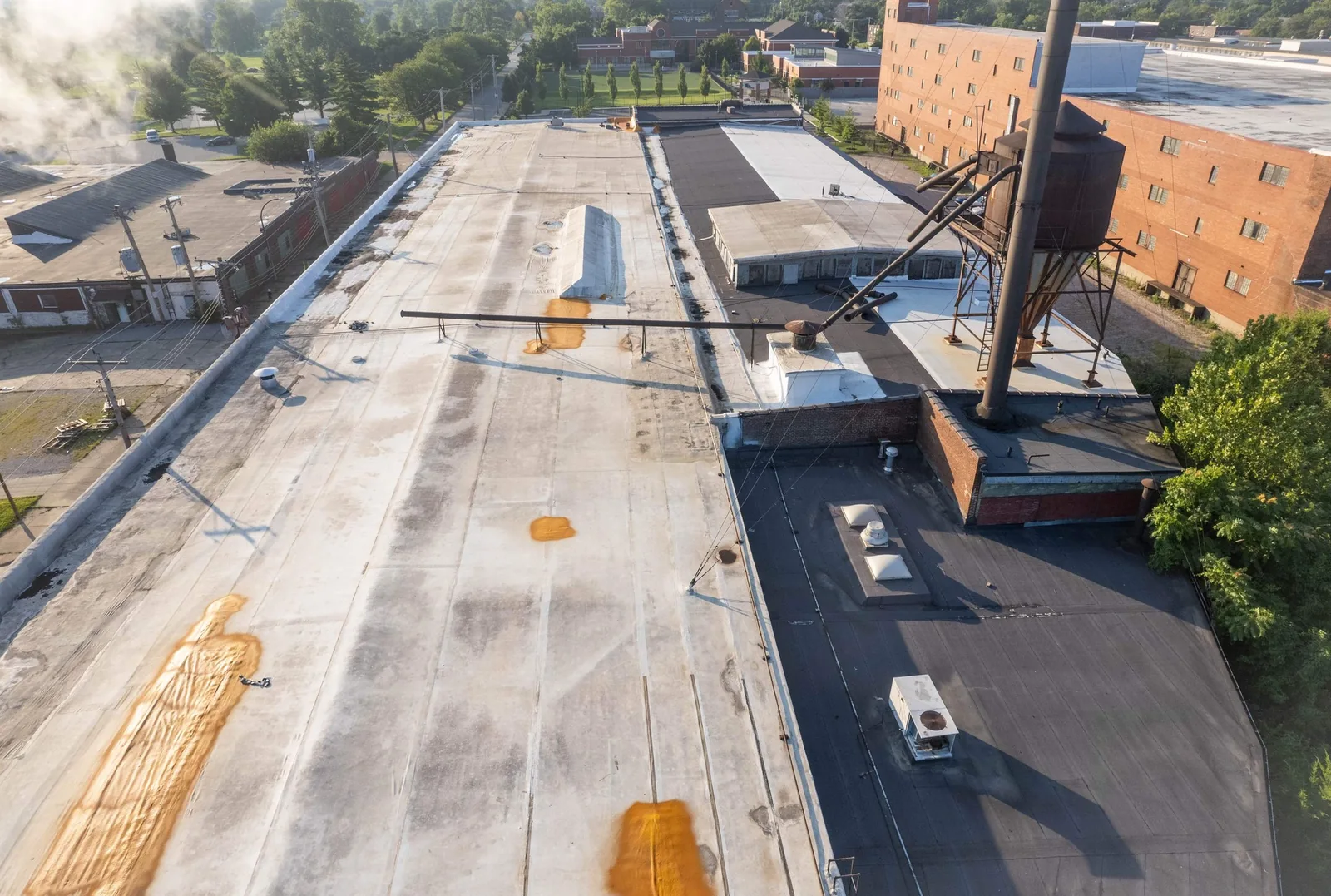 Drone view of a long low-slope roof with staining where water has stood