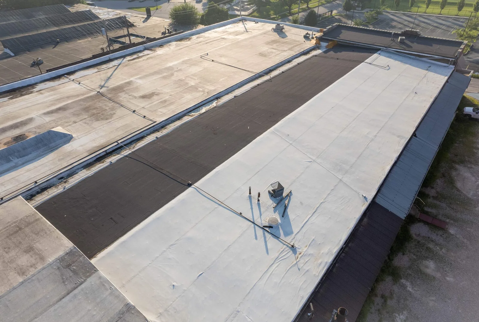 Drone view of a low-slope industrial roof with coated and membrane sections